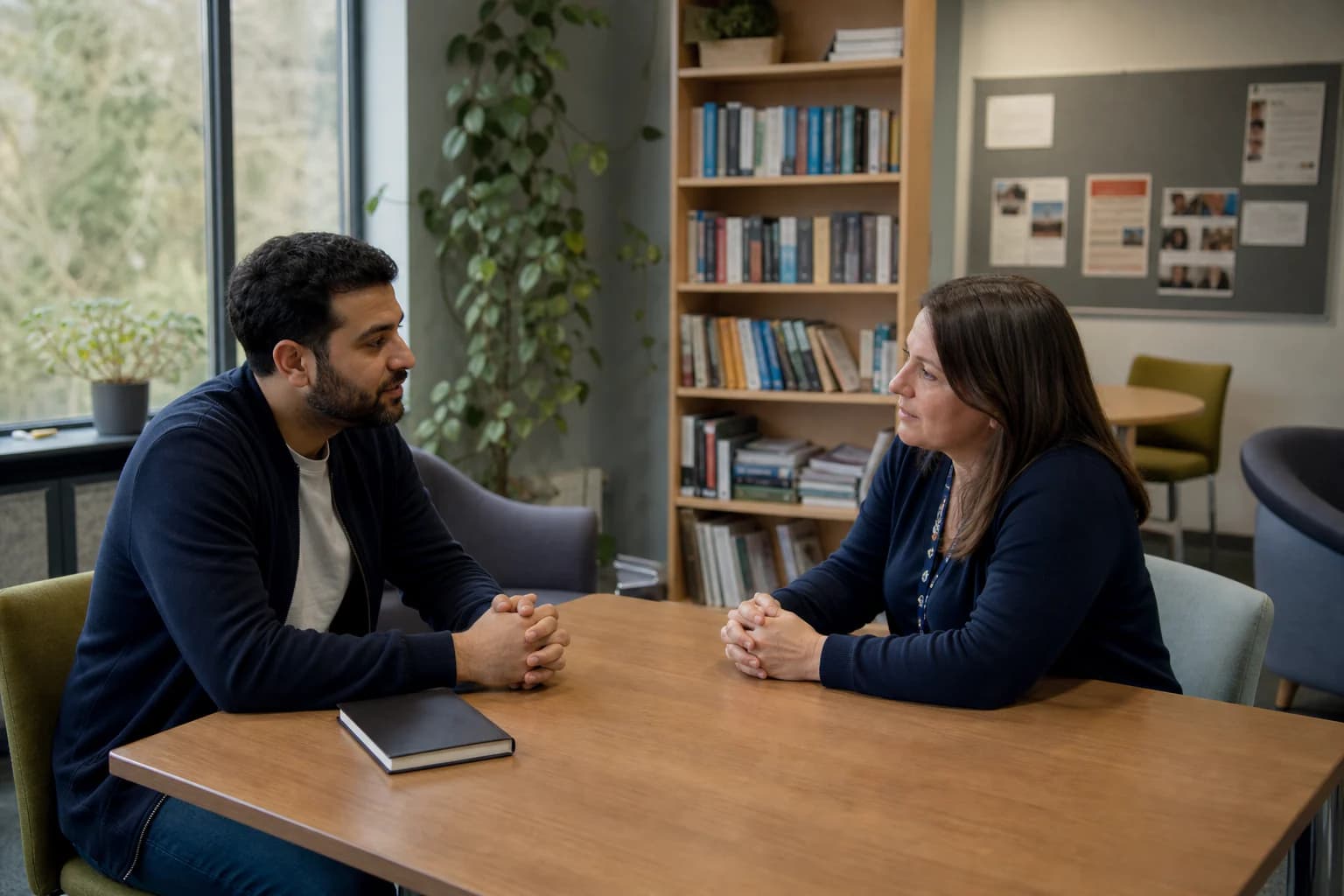 An adult learner has a calm conversation with a student-support adviser in a resource room